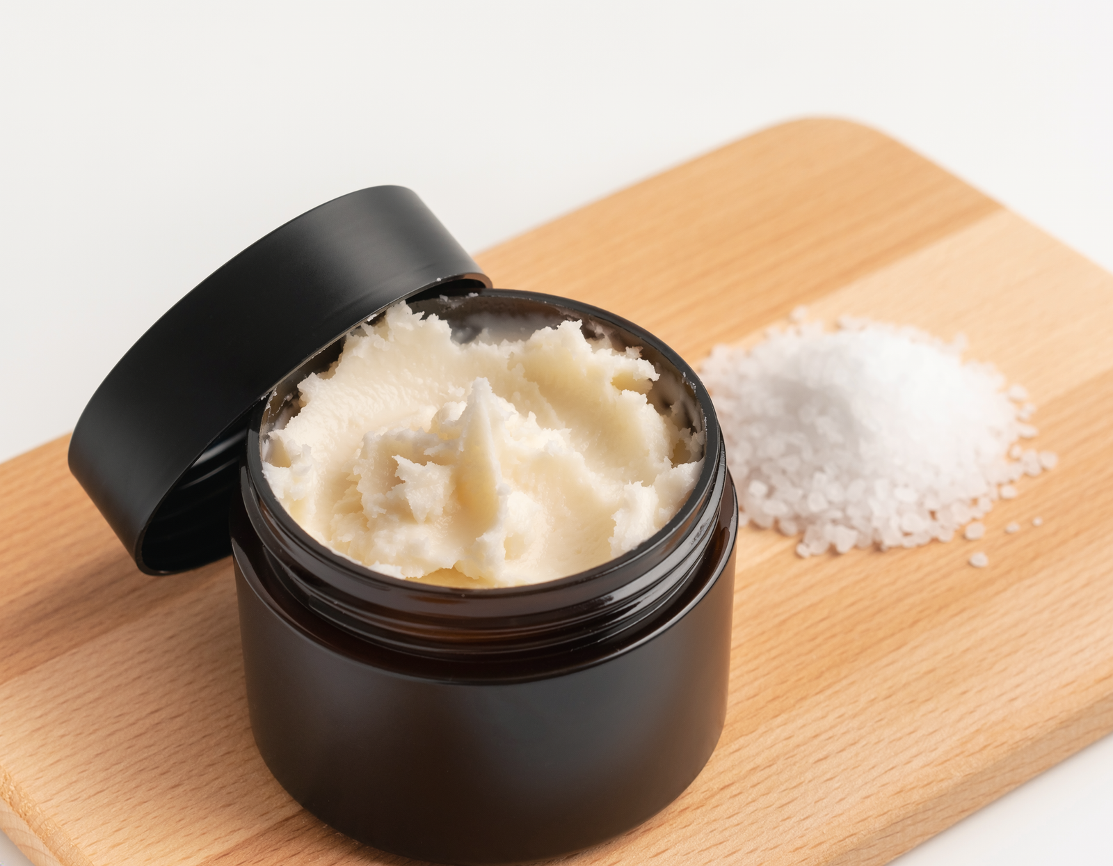 body butter and scrub on a wooden cutting board
